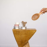 a detangler hairbrush next to personal care items including the tin